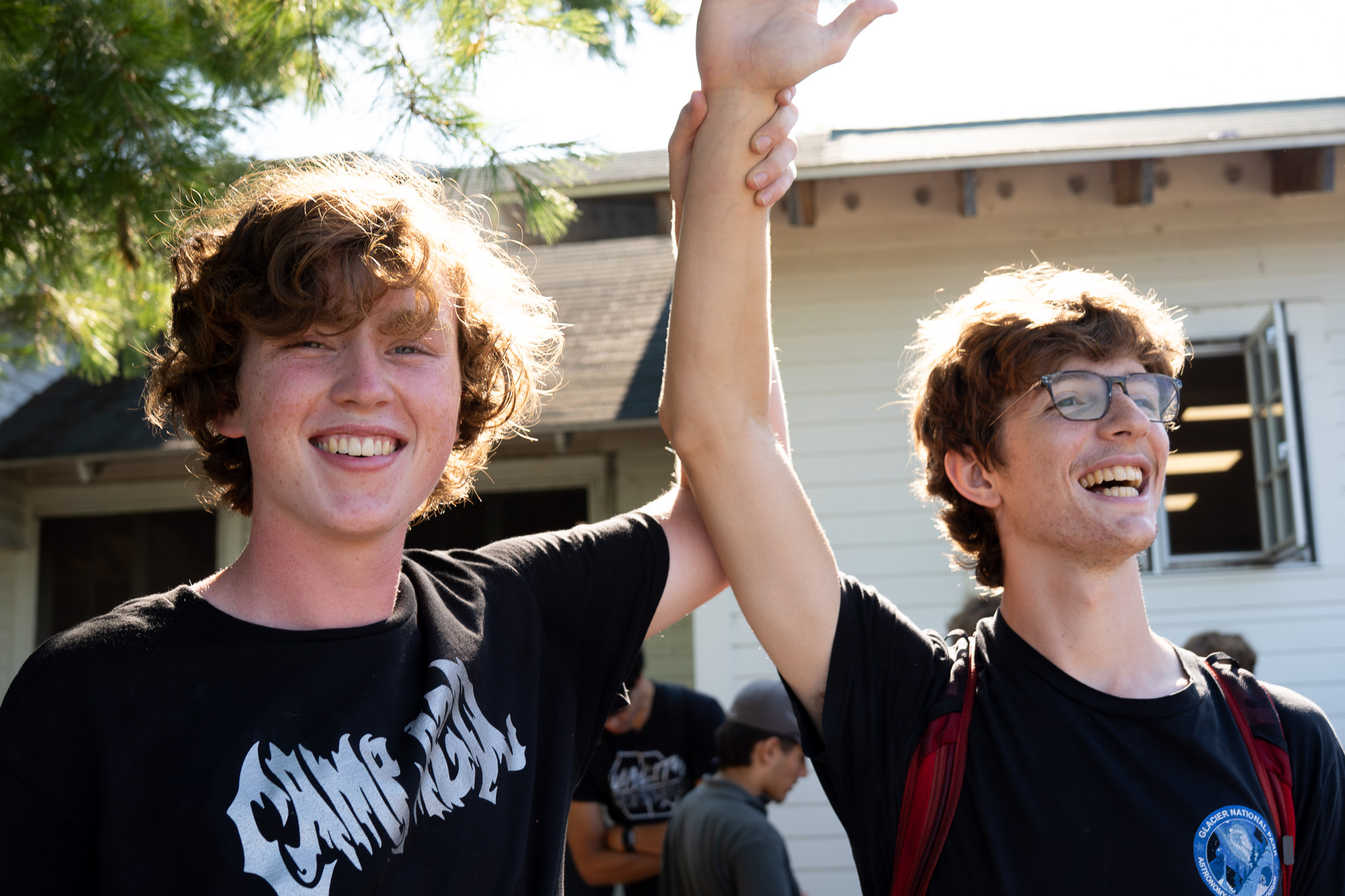 Two Camp AGQ staff members smiling happily in front of the historic dining hall